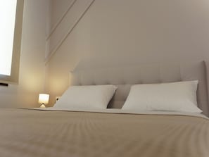 Ein Bett mit Kopfteil, einer Nachttischlampe und einem Fenster.