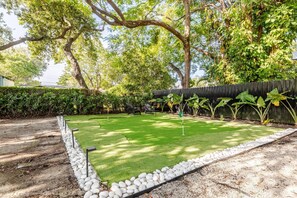 A well-maintained backyard with a putting green, a wooden fence, and a variety of plants. - 4BR Miaminear Design Districtbig Yard & Fire Pit (Miami)