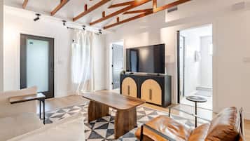 Uma sala de estar moderna com um sofá, uma mesa de centro, uma televisão e um armário.