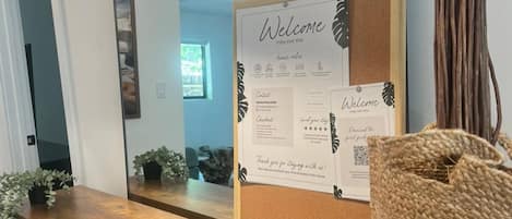 A reception area with a corkboard displaying a welcome message, a framed welcome sign, and a guestbook.