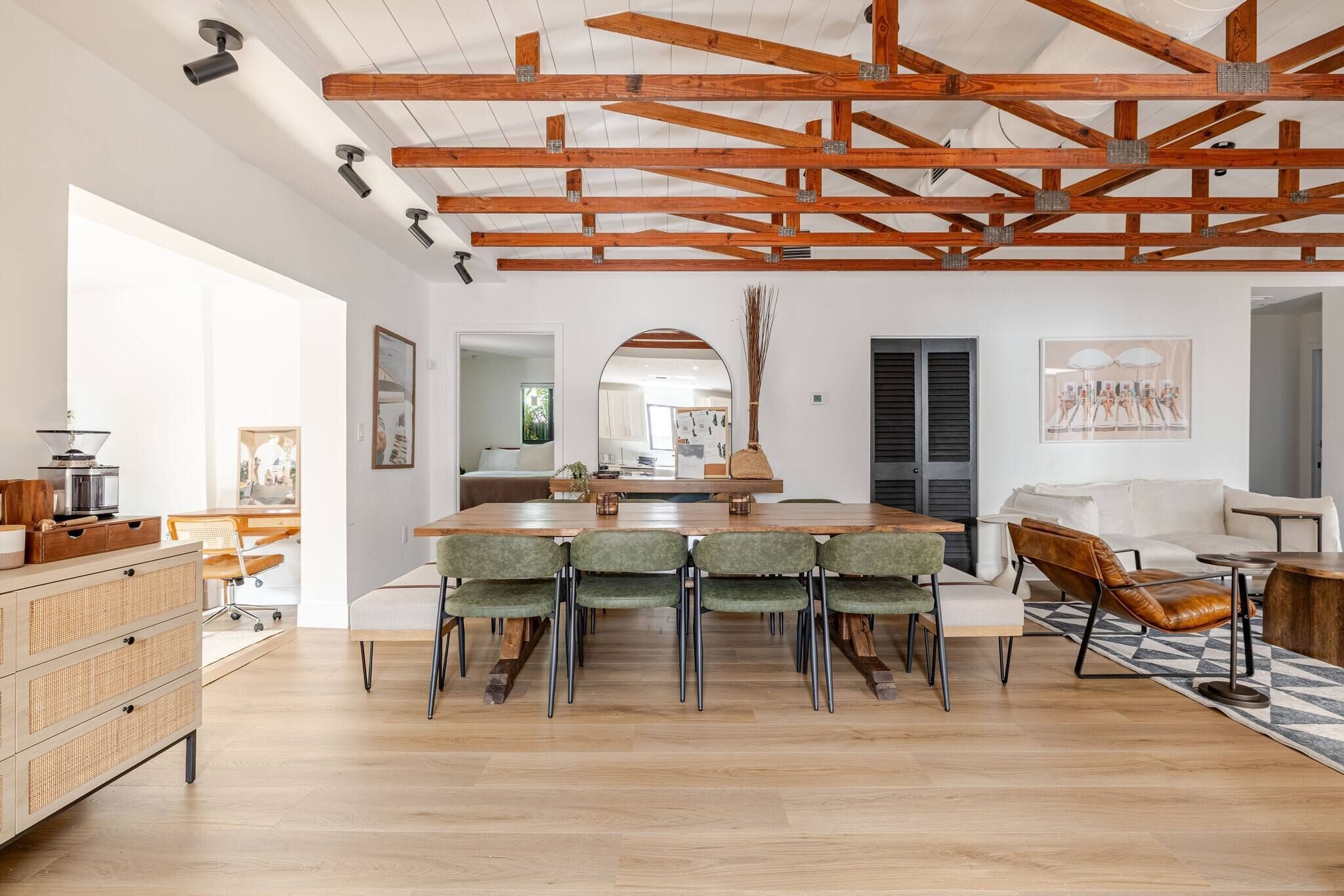 A spacious room with a wooden ceiling, a dining area with a table and chairs, and a sofa.