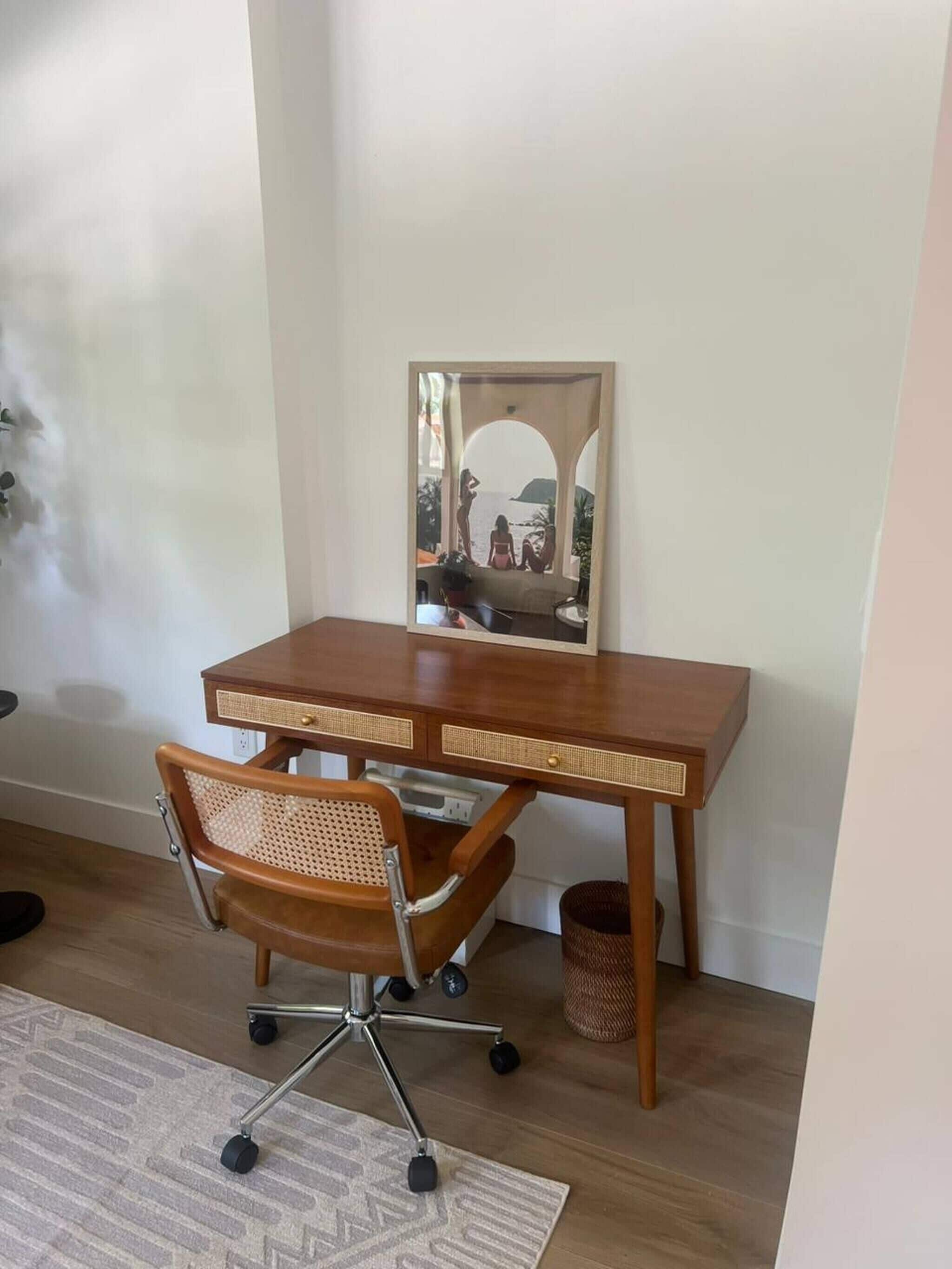 A wooden desk with a chair, a mirror, and a view of the sea.