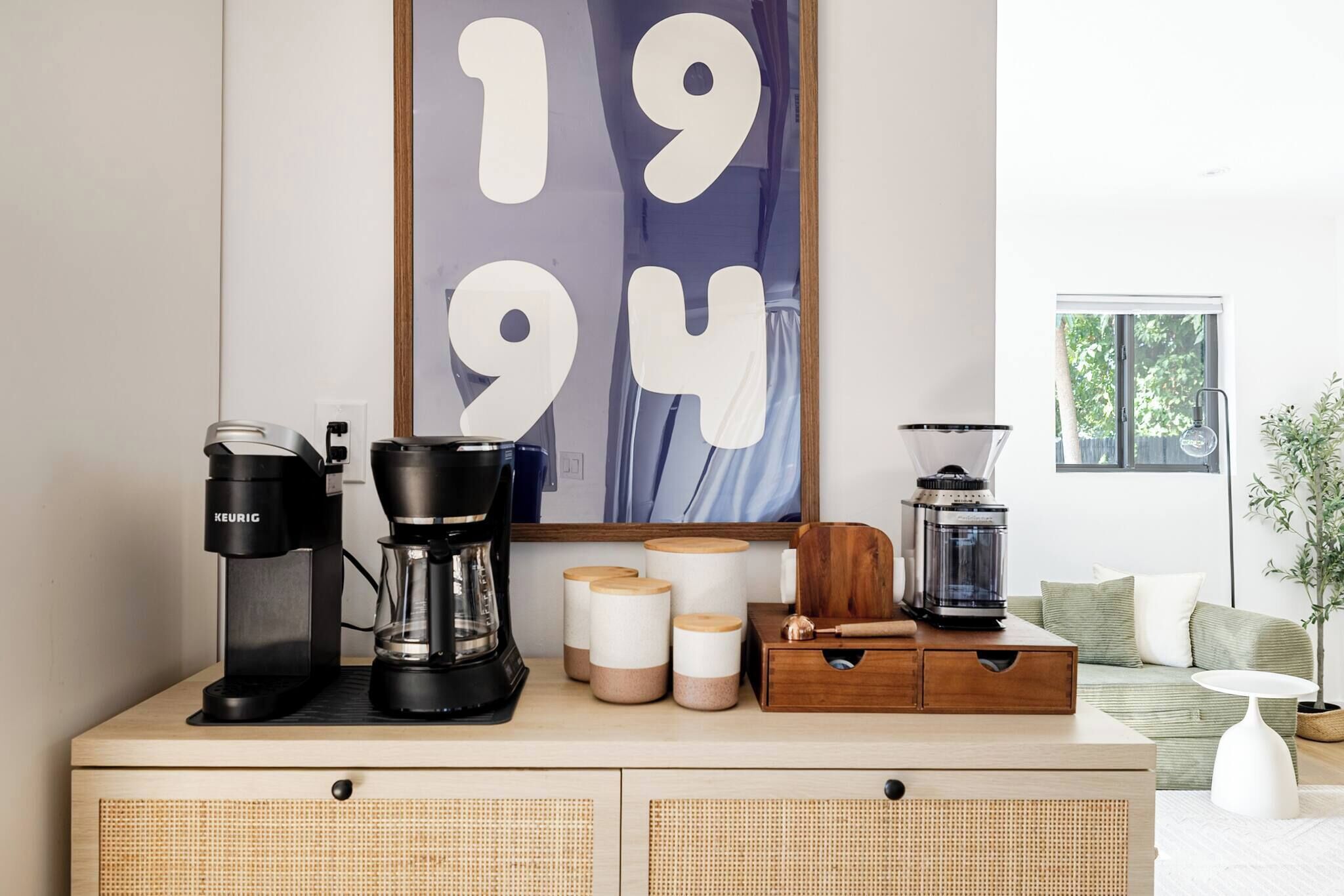 Uma cozinha compacta com cafeteira, liquidificador e recipientes de armazenamento em uma bancada de madeira.
