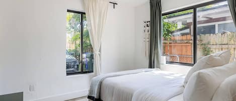 A bedroom with a bed, a window, and a view of the outside.