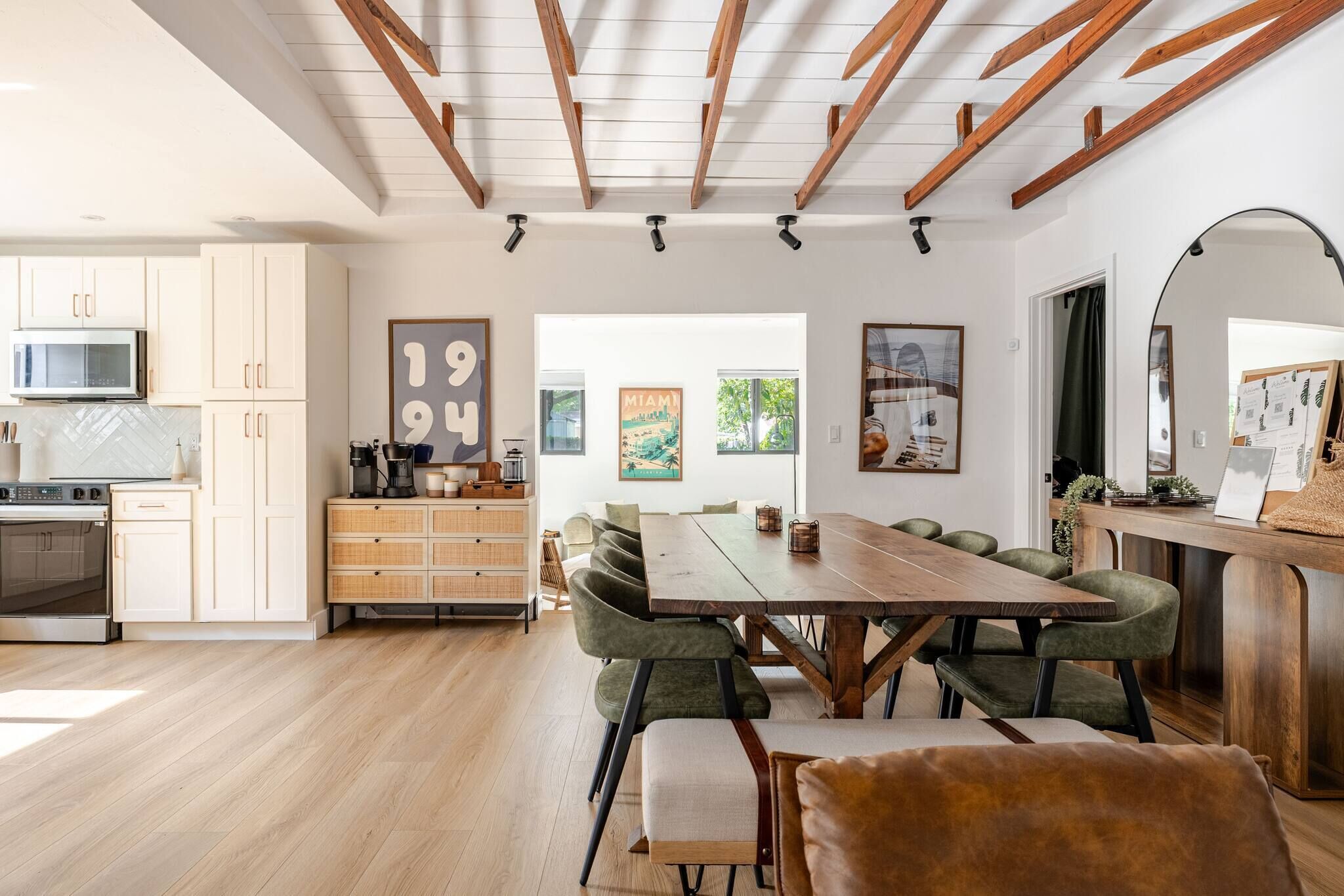 A modern kitchen with white cabinets, a wooden dining table, and a breakfast bar.