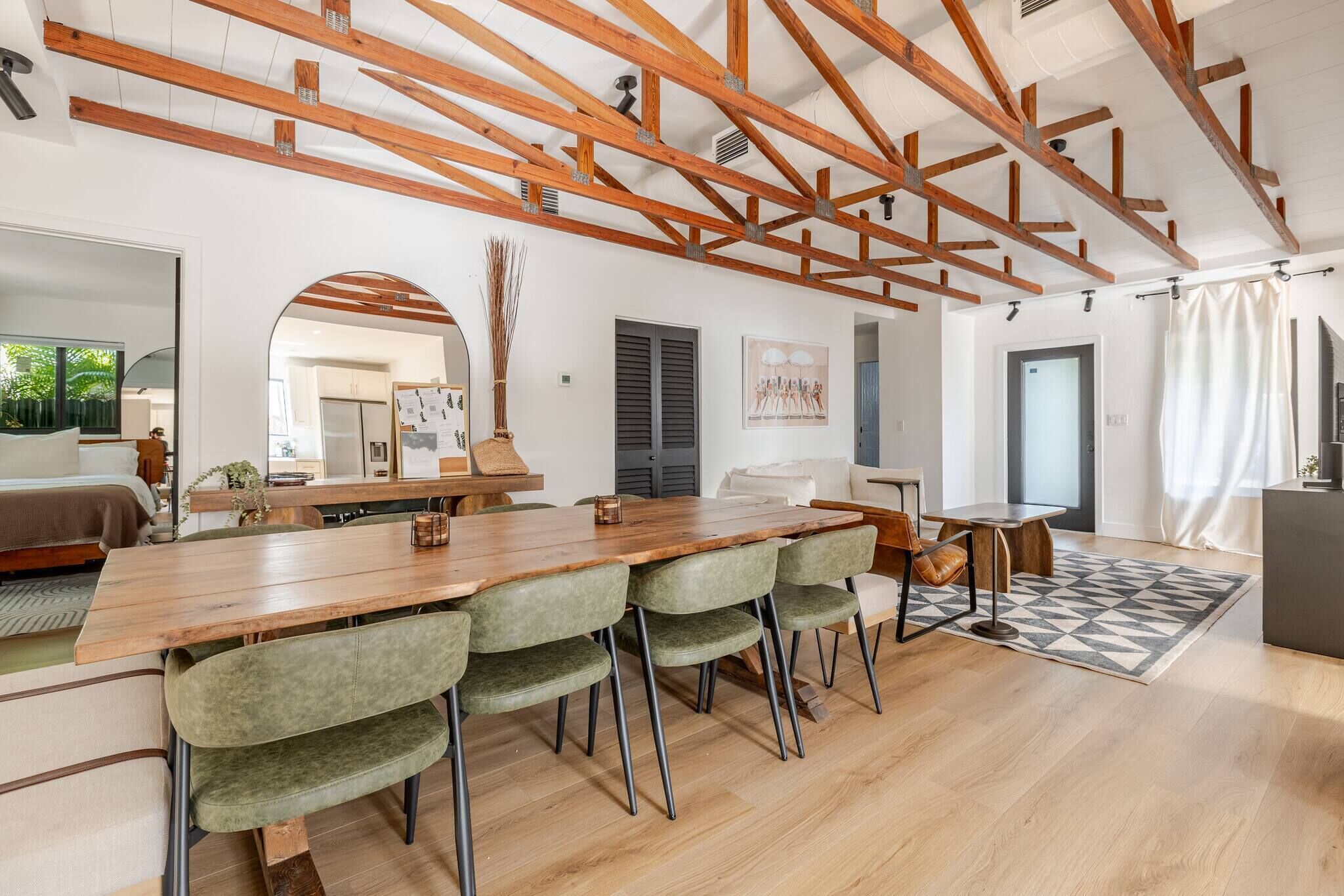 Een modern interieur met een eethoek, bestaande uit een houten tafel en groene fauteuils.