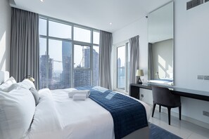 Ein Hotelzimmer mit einem großen Bett, einem Schreibtisch und Blick auf eine Stadtlandschaft.