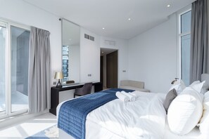 Ein modernes Hotelzimmer mit einem großen Bett, einem Schreibtisch und Blick auf die Stadt.