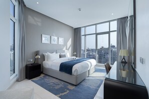 Ein modernes Hotelzimmer mit einem großen Bett, einem Schreibtisch und Blick auf die Stadtlandschaft.