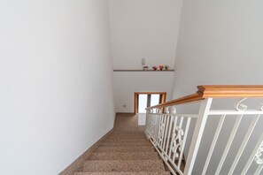 A staircase with a white railing and a wooden handrail, leading to a landing with a small shelf holding decorative items. - Apartment 'Casa Lucia appartamento vacanze' with Sea View, Wi-Fi and Air Conditioning (Avola)