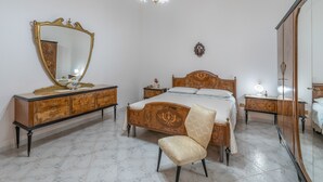 A bedroom with a large mirror, a bed with a wooden headboard, a bedside table, a chair, and a wardrobe. - Apartment Lucia with Sea View, Wi-Fi, and Air Conditioning (Avola)