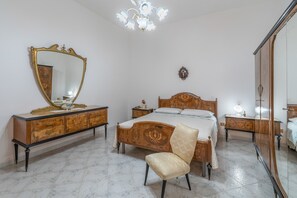 Ein Schlafzimmer mit einem großen Spiegel, einem Bett mit Holz Kopfteil, einem Nachttisch, einem Sessel und einem Kleiderschrank.