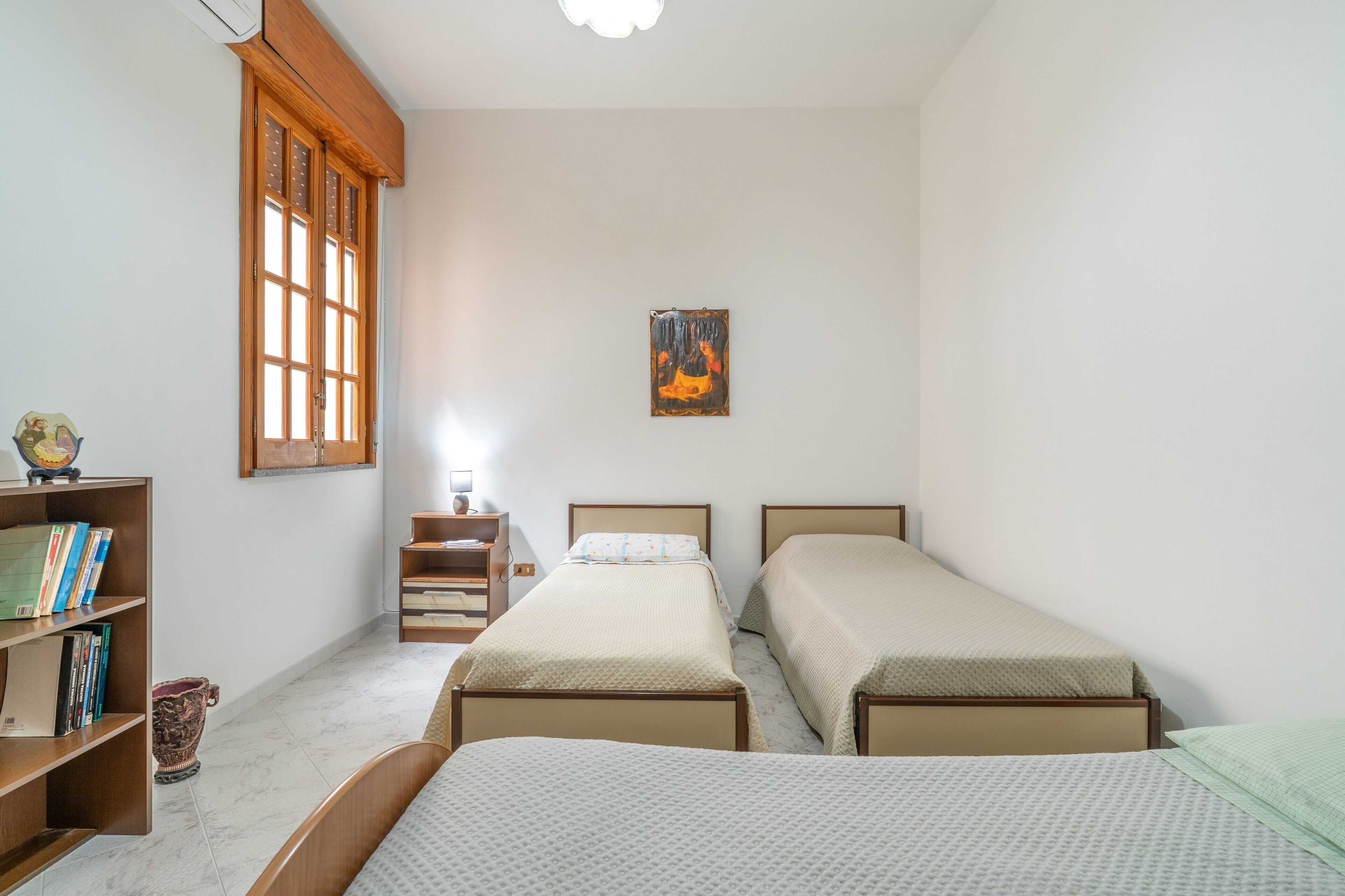 Una camera da letto con due letti singoli, un armadio in legno, un tavolino e una libreria.