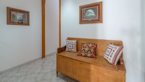 A room with a wooden bench, two framed artworks on the wall, and a marble floor. - Apartment Lucia with Sea View, Wi-Fi, and Air Conditioning (Avola)