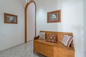 Ein Zimmer mit einer hölzernen Bank, zwei gerahmten Kunstwerken an der Wand und einem Marmorboden.