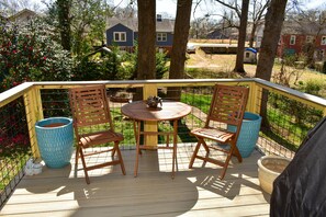 A wooden deck with a round table and two chairs, surrounded by a metal railing. - Greenville's Best Kept Secret (Greenville)