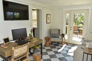 Ein Zimmer mit Schreibtisch, Stuhl, Fernseher und einem Fenster mit Jalousien.
