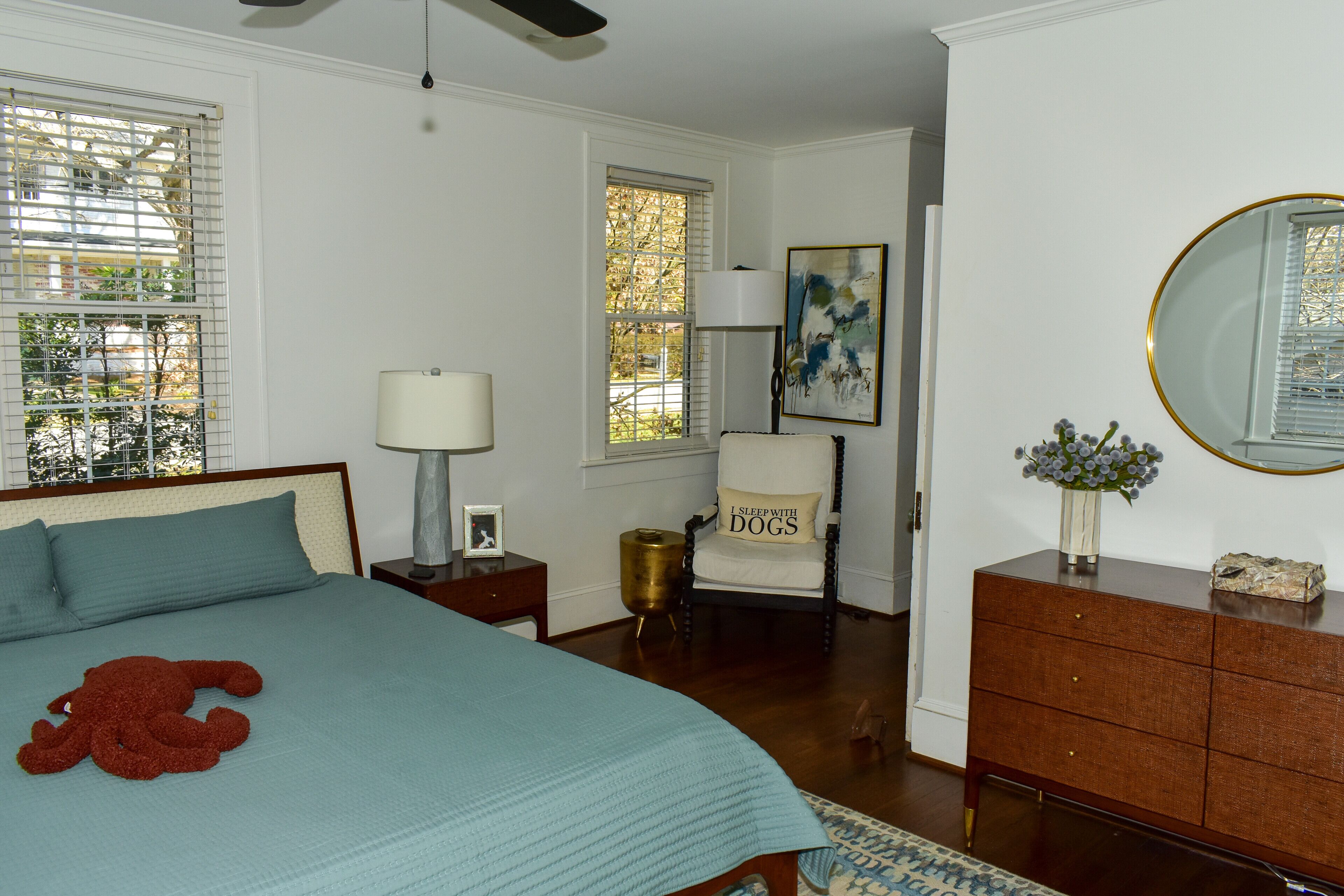 A bedroom with a bed, a chair, a dresser, and a mirror.