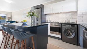 A modern kitchen with a central island, stainless steel appliances, and a built-in washing machine. - The Terraces 220 - Two Bedroom Apartment, Sleeps 4 (Cape Town)