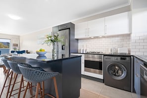 A modern kitchen with a central island, stainless steel appliances, and a built-in washing machine. - The Terraces 220 - Two Bedroom Apartment, Sleeps 4 (Cape Town)