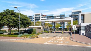 A modern building with a covered entrance, a pedestrian crossing, and a stop sign. - The Terraces 220 - Two Bedroom Apartment, Sleeps 4 (Cape Town)