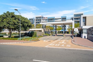 A modern building with a covered entrance, a pedestrian crossing, and a stop sign. - The Terraces 220 - Two Bedroom Apartment, Sleeps 4 (Cape Town)