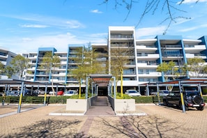 Un edifici residencial modern de diversos pisos amb entrada coberta i zona d'aparcament.