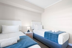 Habitació d'hotel amb dos llits, una taula de nit i una làmpada.