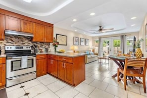 A modern kitchen with wooden cabinets, a built-in oven, and a dining area with a table and chairs. - Steps to Maui's Charley Young Beach Condo Apt 1 (Kihei)