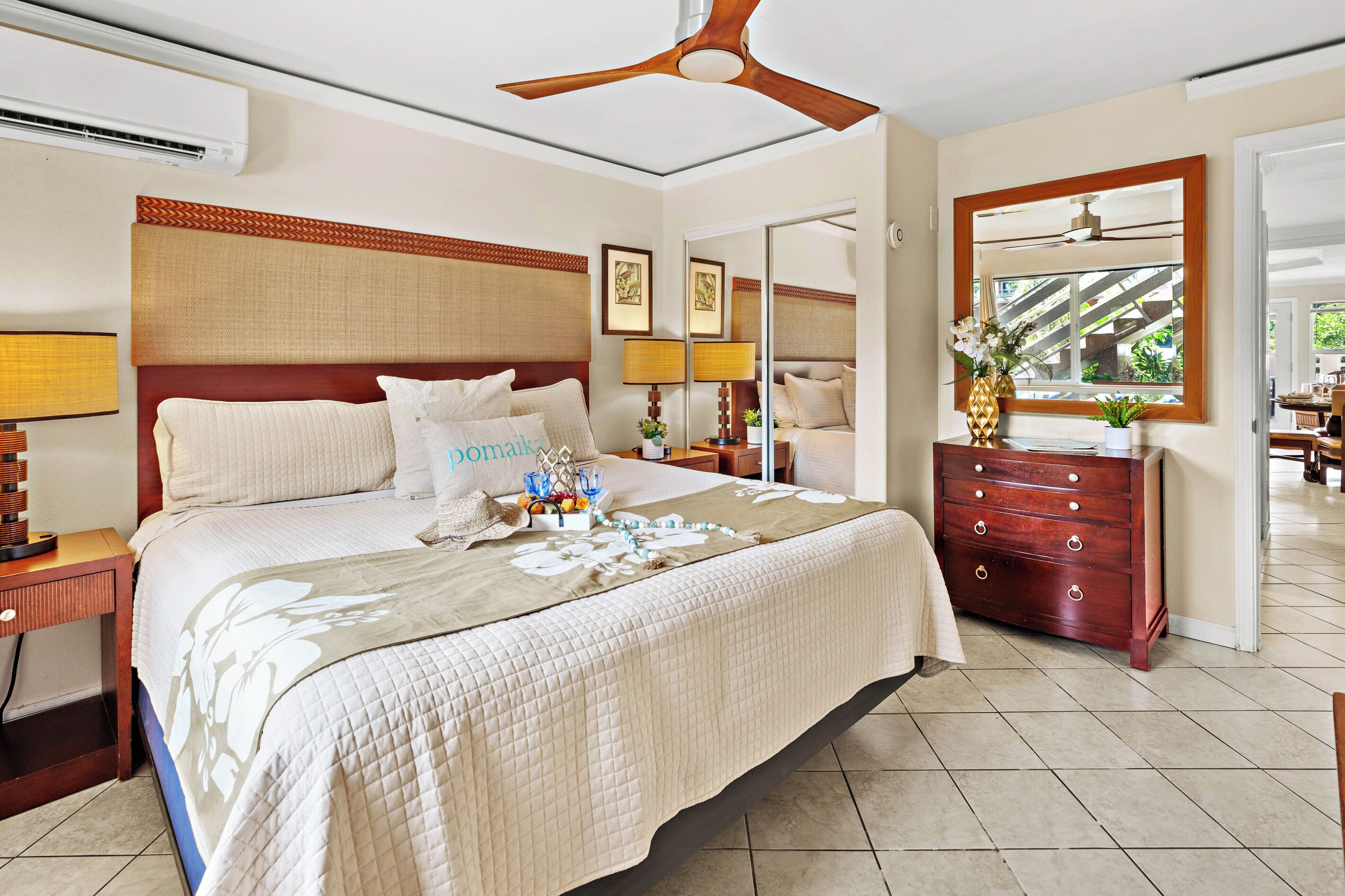A hotel room with a bed, bedside tables, a dresser, a ceiling fan, and a window with a view.