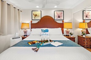 Ein Hotelzimmer mit einem großen Bett, zwei Nachttischlampen, einem Dekokissen, einem Nachttisch mit einer Vase und einer Wand mit gerahmten Kunstwerken.