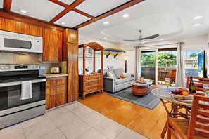 A modern kitchen with a microwave, stove, and wooden cabinets. - Steps to Maui's Charley Young Beach Condo Apt 5 (Kihei)