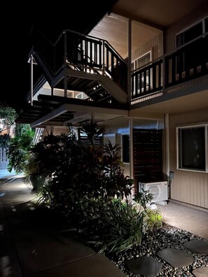 A multi-story building with outdoor staircases and a garden area with potted plants. - Steps to Maui's Charley Young Beach Condo Apt 6 (Kihei)