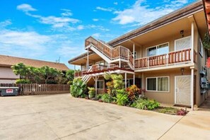 A two-story building with a central staircase, a covered outdoor area, and a parking lot. - Steps to Maui's Charley Young Beach Condo Apt 6 (Kihei)