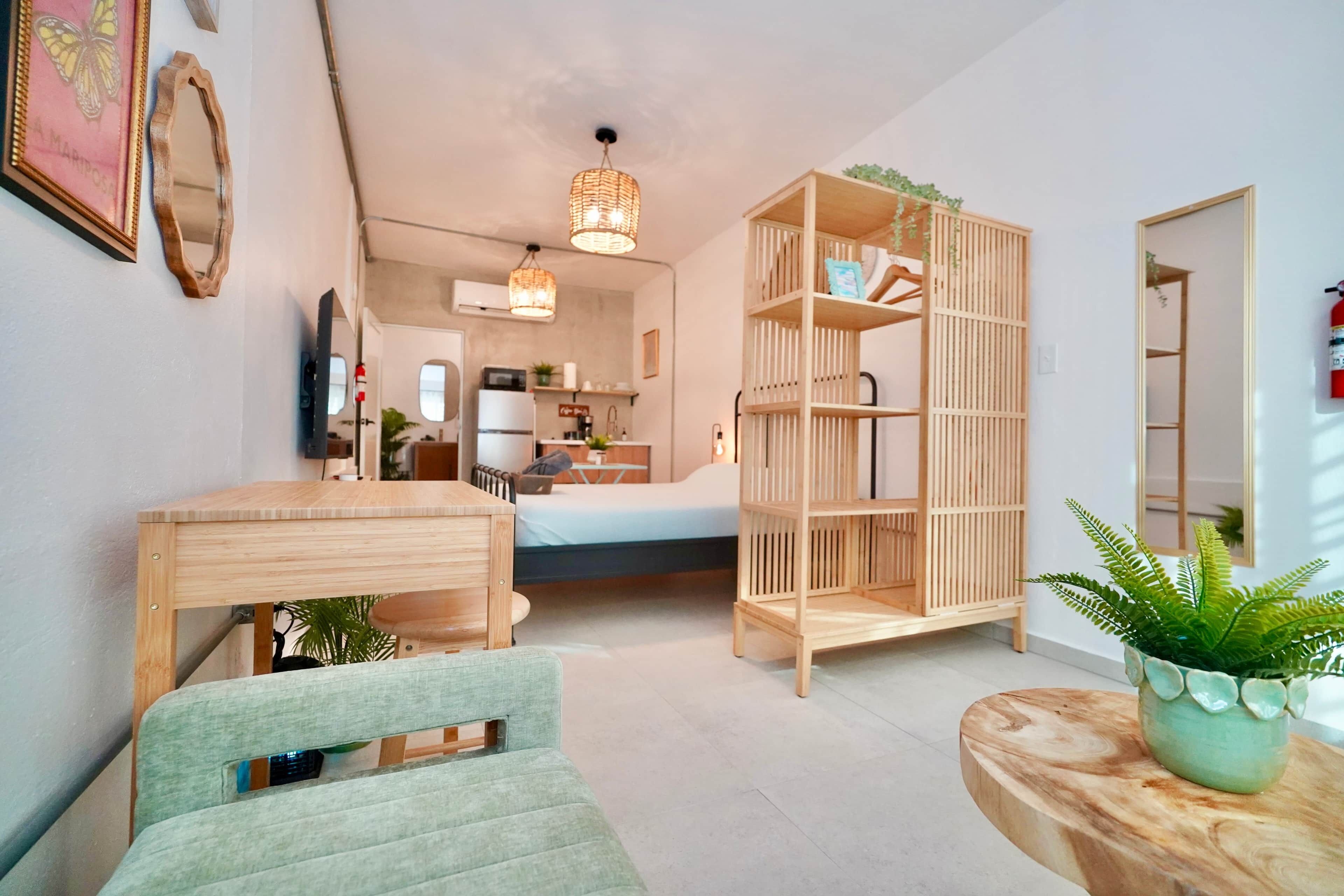 Een knus woongedeelte met een bed, een eettafel, een boekenkast en een klein keukenhoekje.