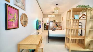 Ein gemütlicher, kompakter Wohnraum mit Bett, Holzschreibtisch, Tisch und Regalelement.