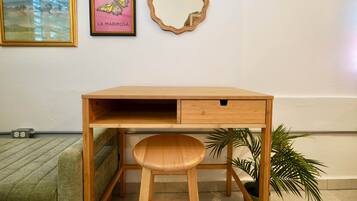 Un bureau en bois avec un tiroir, un miroir et deux œuvres d’art encadrées accrochées au mur.
