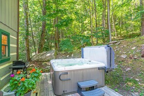 A hot tub in a forested area with a wooden deck and a window. - Tucked Away- Cabin, Pet Friendly, Hot Tub, Wood Fireplace. Fire-pit, Covered Por (Boone)