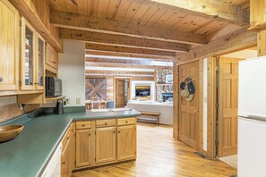 A kitchen with wooden cabinets, a microwave, and a dining area with a table and chairs. - Tucked Away- Cabin, Pet Friendly, Hot Tub, Wood Fireplace. Fire-pit, Covered Por (Boone)