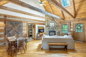A log cabin interior with a dining area, a fireplace, and a bed. - Tucked Away- Cabin, Pet Friendly, Hot Tub, Wood Fireplace. Fire-pit, Covered Por (Boone)