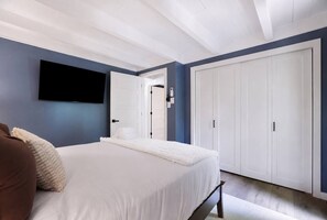 A bedroom with a bed, a flat-screen TV mounted on the wall, and a wardrobe. - Pocono Lake Escape | Hot Tub, Games & Outdoor Fun (Monroe County)