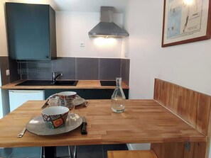 A compact kitchen with a modern design, featuring a built-in oven, a sink, and a stainless steel range hood. - Charming Little House Near the Beach and Forest (La Tranche-sur-Mer)