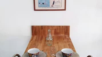 A dining table with two chairs, a framed instructional poster, and a hanging light fixture.