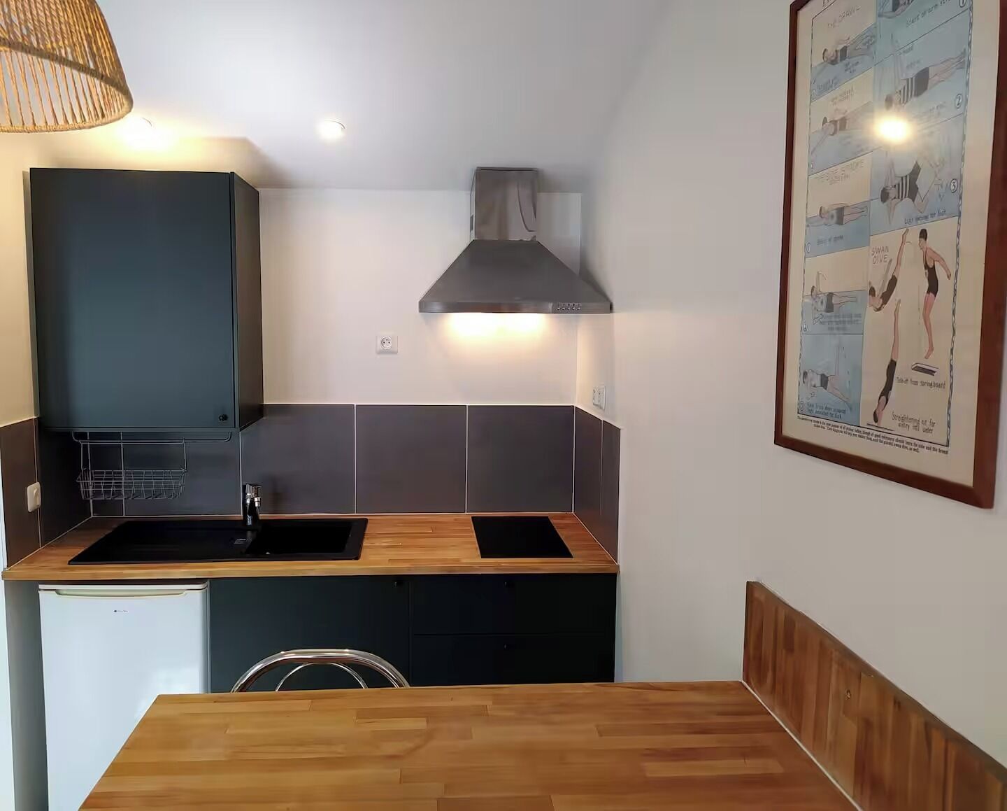 Une petite cuisine équipée d’un évier, d’une cuisinière et d’un petit réfrig érateur.