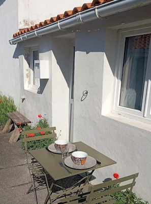 An outdoor dining area with a table and chairs, a window, and a door on a building.