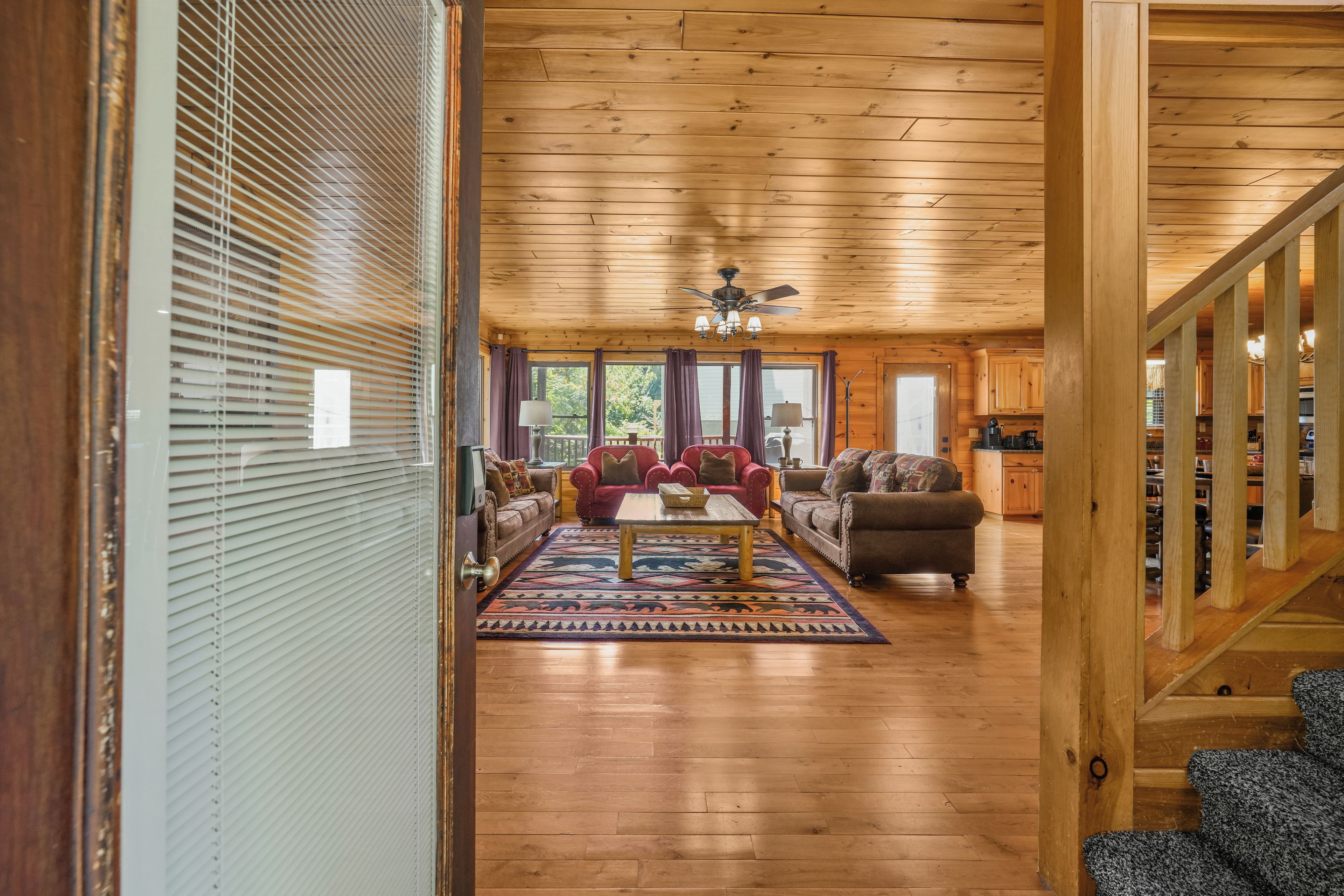 A wooden-floored living room with a sofa, armchairs, and a coffee table.