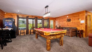 A pool table in a room with wooden walls and a view of the outdoors. - Mountain Views & Hot Tub | 1 Mi to Ober (Gatlinburg)