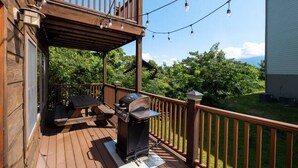 A wooden deck with a barbecue grill, outdoor seating, and string lights. - Mountain Views & Hot Tub | 1 Mi to Ober (Gatlinburg)