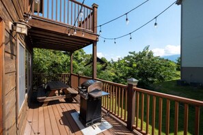 A wooden deck with a barbecue grill, outdoor seating, and string lights. - Mountain Views & Hot Tub | 1 Mi to Ober (Gatlinburg)