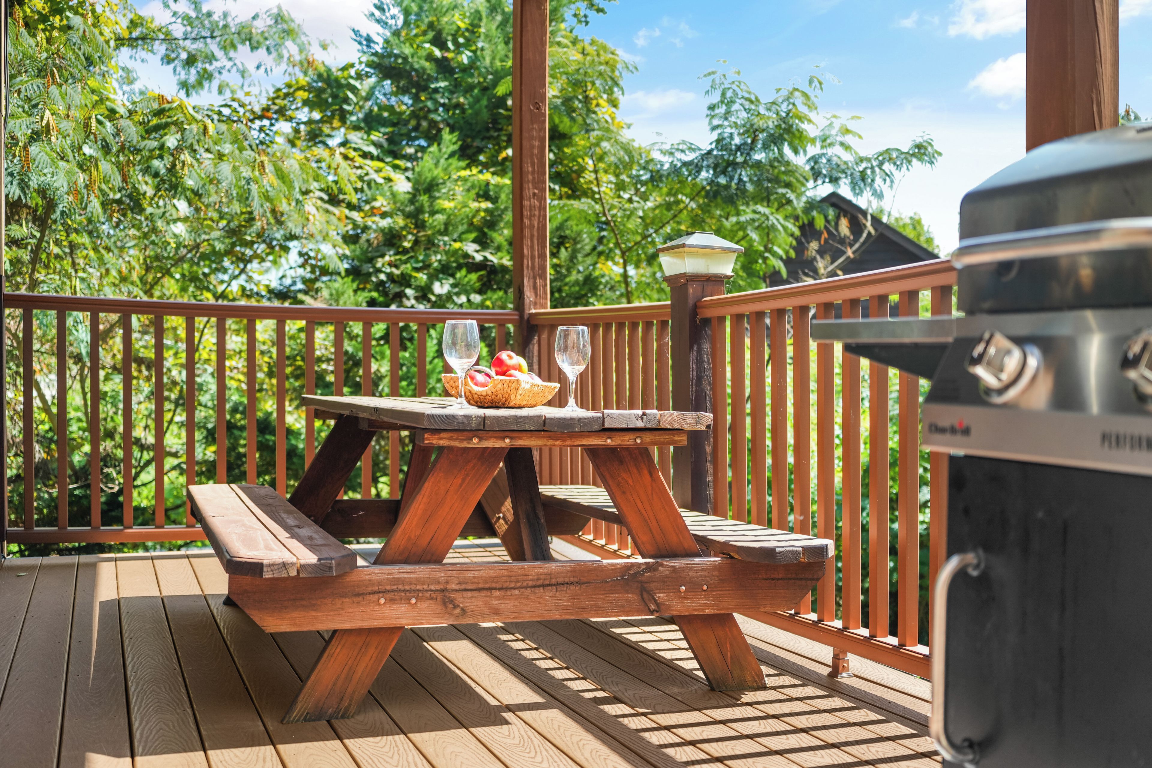 Une terrasse en bois avec une table de pique-nique, un barbecue et un lampadaire.